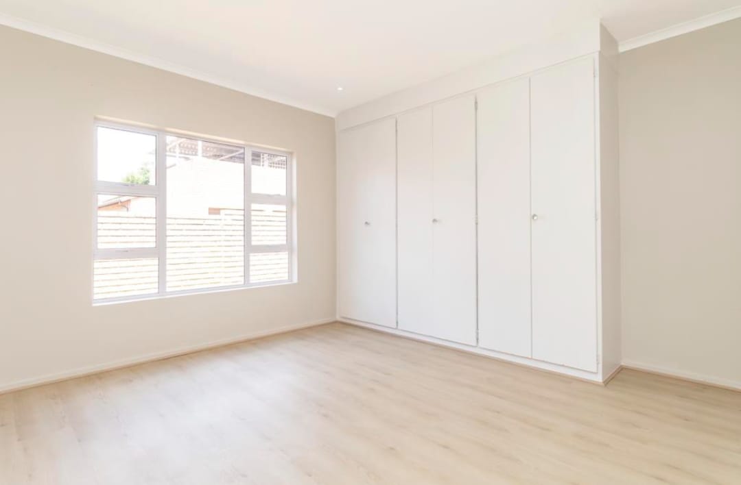 Bedroom with built-in white wardrobes and light wood flooring